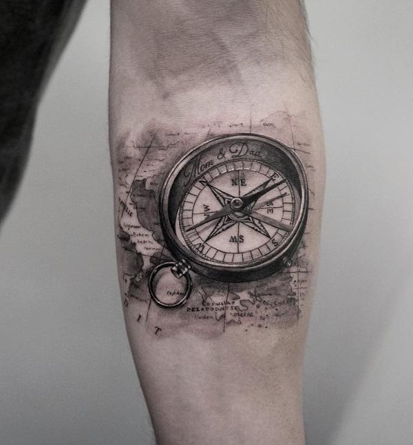 Svart og grå liten tatovering med kompass og kart på underarm
