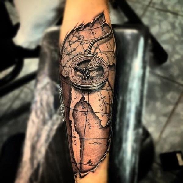 Utrolig carving -tatovering med verdenskart og nautisk kompass på underarmen