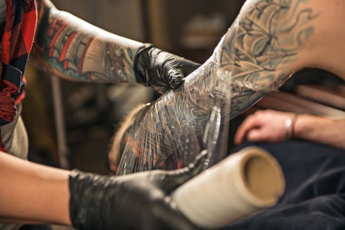 Etter at du har mottatt din splitter nye tatovering, vil artisten pakke den inn for å holde den beskyttet. Hver tatoverer har sine egne anbefalinger for hvor lenge du skal beholde omslaget - så spør artisten din hvis du er i tvil. Uansett må du holde det nye blekket pakket inn i minst et par timer, om ikke over natten.
