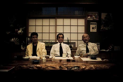 A család három legmagasabb rangú főnöke - a Keresztapa a középpontban - portréra pózol egy hagyományos vacsora közben egy étteremben Kabukichoban, Tokióban - 2009