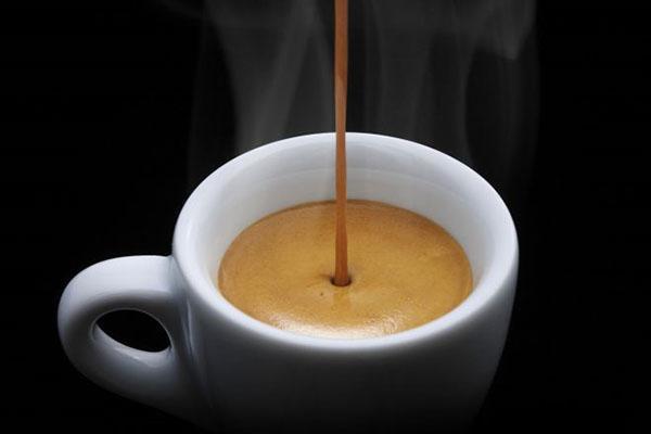 giet koffie in een kopje melk