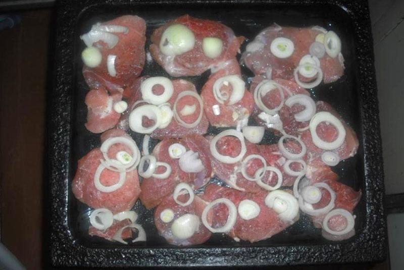 leg het vlees en de uien op een bakplaat