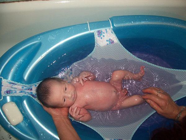 een pasgeboren baby in een hangmat baden