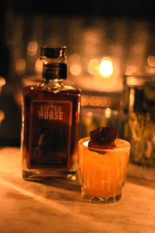 The Paddock Cocktail utviklet av Destinee Almonte, No Vacancy LA*· 1 oz. The Gifted Horse American Whisky ·. 25 oz. Fløyel Falernum · 1 kvarter stekt pære · 2 bar skjeer sukker · 1 dash kardemommebitter · Toppet med brus Pynt med en sukkerpære.