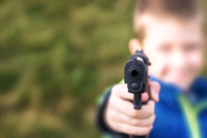 ung gutt som peker pistol mot kameraet