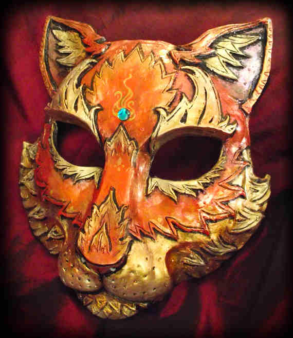 CAT MASK Støpt maske. Håndmalt og håndskulpturert. Dette har et slags brann -tema som pågår med gullglans til oransje. Perlen er et stykke av den blå abalonen. Denne masken dekker det meste av ansiktet. Bredden over øynene er omtrent 6