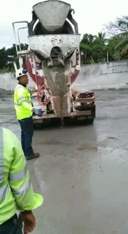 Két dolgozó türelmesen várja, hogy a cementcsúszda eltömődjön.