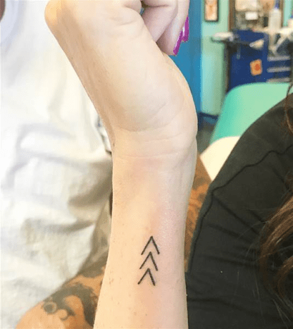 Photo @micamayMay, aki tervező, úgy döntött, hogy megtervezi a tetoválásait, és nagy erőfeszítéseket tesz a tetoválás létrehozásában. Végül három nyíl mellett döntött, először a Down -szindrómás emberek 2121 -es kromoszómáját szimbolizálva, valamint a fogyatékosság híveit arra, hogy folytassák a haladást.